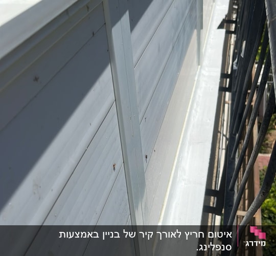 קיר חיצוני עם ציפוי מתכת ומעקה ברזל